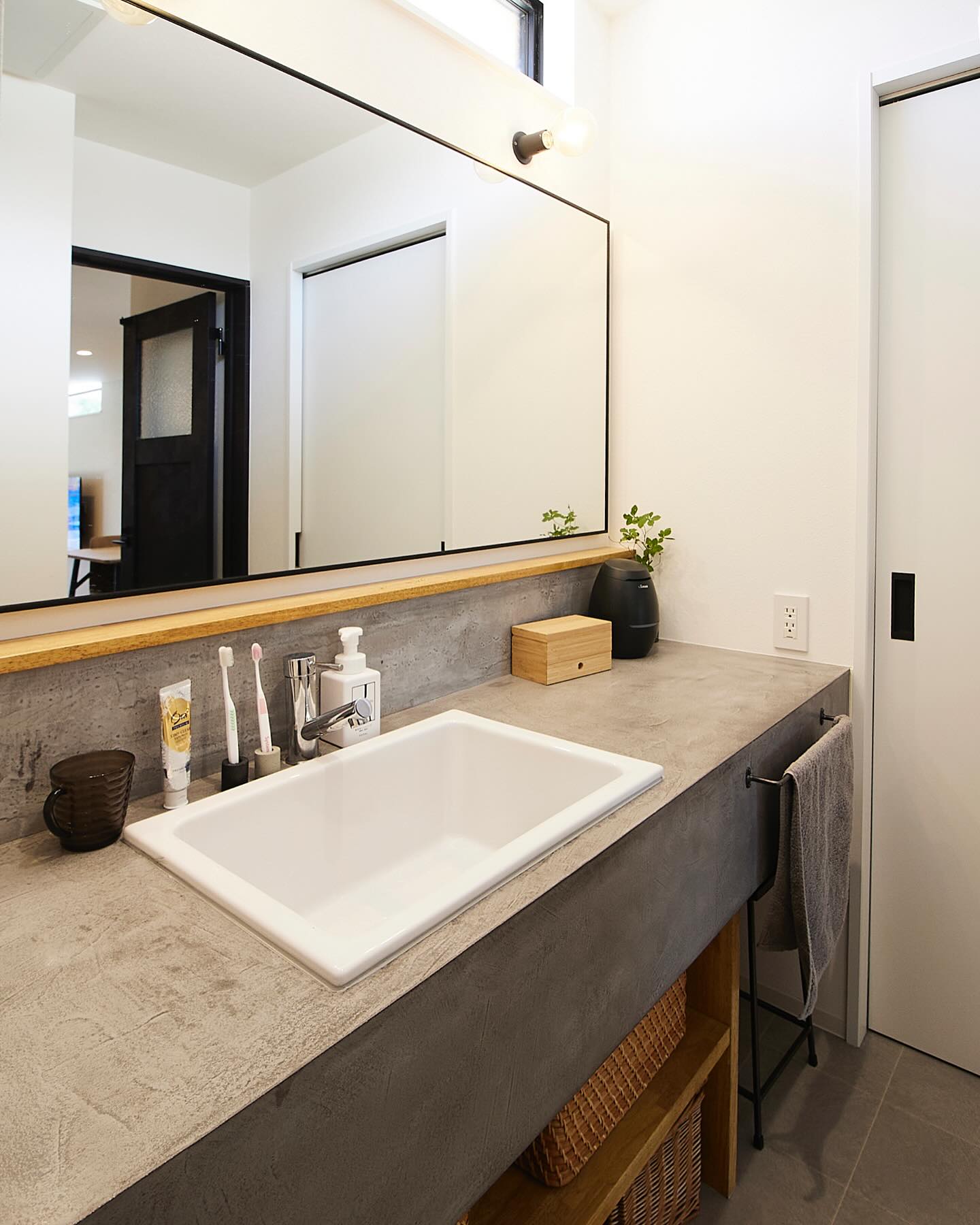 無機質なコンクリート調のカウンターと、温もりを感じる木のアクセントが絶妙に調和した洗面スペース。
大きなミラーが空間を広く見せ、ブラックフレームの照明が洗練された雰囲気を演出します。
デザイン性だけでなく、オープン収納やタオルバーなど、使い勝手にもこだわった設計。
#洗面台 #おしゃれな洗面所 #注文住宅 #インテリアデザイン #洗練された暮らし